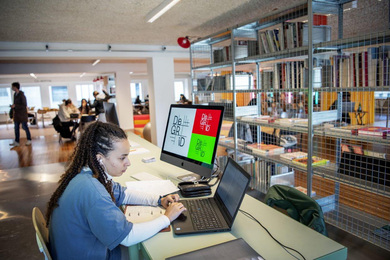 Een persoon werkt aan een laptop in het Medialab (zone van De Grid, de doe- en maakplek van Muntpunt)